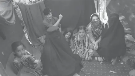  ?? RAHMAT GUL/AP ?? Displaced school teacher Nilofar, in a burqa on the left, sits in her tent with others Friday at a park in Kabul amid the Taliban advance.