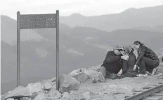  ?? Jerilee Bennett, The Gazette via The Associated Press ?? Mandy Horvath, center, is hugged by her mother and father, Lisa and Clay, after she finished climbing Pikes Peak on June 13. Her parents greeted the amputee at the summit.