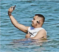  ?? STAFF PHOTOS BY PATRICK WHITTEMORE ?? SEA SELFIE: Revere resident Ricardo Alvarez was all smiles as he made a saline selfie off the shoreline at Revere Beach.