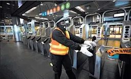  ?? SPENCER PLATT/GETTY ?? A worker closes a New York City subway station on Wednesday for cleaning.