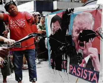  ?? Erik de Castro/Reuters ?? Manifestan­tes jogam tinta em fotos de Duterte e Trump em ato contra os líderes em Manila