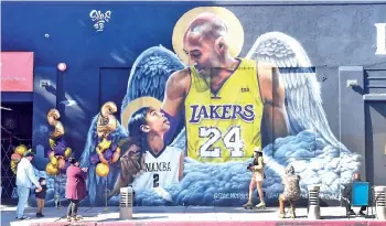  ?? - AFP photo ?? People gather in front of a mural of former Los Angeles Laker Kobe Bryant and his daughter Gianna, to mark their one-year death anniversar­y.