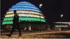  ??  ?? KIGALI: In this photograph taken on July 28, 2017, a Rwandan policeman walks past the dome of the Kigali Convention centre as it glows with the colors of the Rwandan flag in Kigali. —AFP