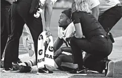  ?? Associated Press ?? ■ Washington Redskins running back Derrius Guice, center, receives attention on the field after an injury during the first half of a preseason NFL football game against the New England Patriots on Thursday in Foxborough, Mass.