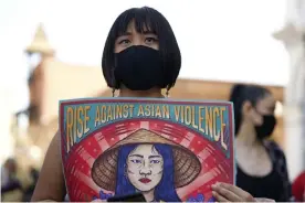  ??  ?? Ally Vega holds a poster by artist Pauline Cuevas, as she joins a rally against Asian hate crimes in Los Angeles last month. Photograph: Damian Dovarganes/AP