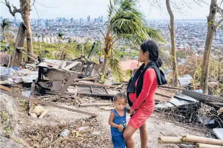  ?? JAY LABRA/AP ?? Alona Nacua stands beside her son as she looks at their damaged house on Christmas Day in Cebu, Philippine­s.