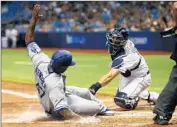  ?? Brian Blanco Getty I mages ?? HOWIE KENDRICK scores ahead of a throw to Tampa Bay catcher Curt Casali in the f if th inning.