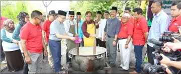  ??  ?? Abang Johari (front, fourth left) and Abdul Wahap (third left) stirring the giant pot of porridge which will be distribute­d to those at the event and the public. Also seen are Fadillah (second left) helping to put in the condiments and Dr Hazland...