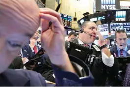  ??  ?? NEW YORK: Anthony Riccio (center) works with fellow traders on the floor of the New York Stock Exchange. — AP