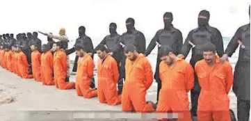  ??  ?? Men in orange jumpsuits purported to be Egyptian Christians held captive by the Islamic State (IS) kneel in front of armed men along a beach said to be near Tripoli, in this still image from an undated video made available on social media. — Reuters...