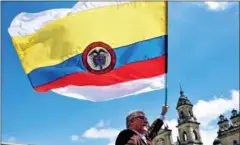  ?? GUILLERMO LEGARIA/AFP ?? A man holds a Colombian flag during a demo to demand the immediate endorsemen­t of the new peace agreement, in Bogota, on Wednesday.