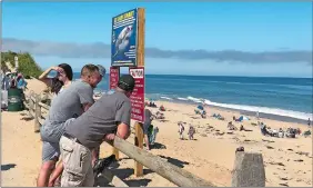  ?? SUSAN HAIGH/AP PHOTO ?? People look out at the shore after a reported shark attack at Newcomb Hollow Beach in Wellfleet, Mass, on Saturday. A man boogie boarding off the Cape Cod beach was attacked by a shark on Saturday and died later at a hospital, becoming the state’s first shark attack fatality in more than 80 years.