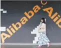 ?? — Reuters ?? An woman walks past a wall painted with logo of Alibaba (China) at its head office in Hangzhou.