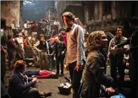  ??  ?? Oscar-winning director Tom Hooper, center, and Daniel Huttleston­e, right, as Gavroche on the set of “Les Miserables.”