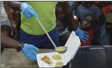  ?? ODELYN JOSEPH — THE ASSOCIATED PRESS ?? A server ladles soup into a container as children line up to receive food at a shelter for families displaced by gang violence in Port-au-prince, Haiti, on Thursday.