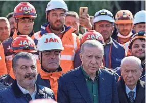  ?? YASIN AKGUL/AFP VIA GETTY IMAGES ?? Turkish President Recep Tayyip Erdogan stands with rescue workers as he visits the hard-hit southeaste­rn province of Hatay Monday. His visit came before a new 6.4 magnitude quake hit the area.