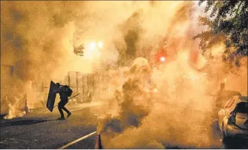  ?? NOAH BERGER/AP ?? A Black Lives Matter protester uses a shield as federal agents use chemical irritants on the crowd Friday in Portland.