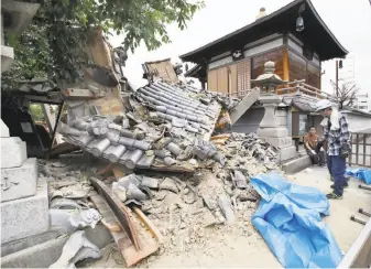  ?? Yosuke Mizuno / Kyodo News ?? Workers gather debris where the gate of a temple collapsed in Ibaraki after the earthquake hit.