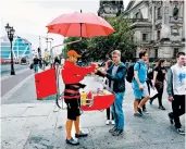  ?? RICK STEVES/RICK STEVES’ EUROPE ?? Sampling one of Germany’s hundreds of varieties of sausage from a street vendor is a classic German experience.