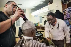  ??  ?? Dr. Joseph Ravenell talks with a customer at a Harlem barbershop as part of the community engagement project.