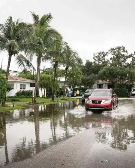  ?? EMILY MICHOT Miami Herald file ?? A car drives north along Northeast 10th Place near 105th Street, where the roads frequently flood during King Tides.