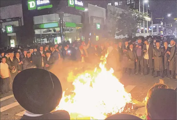  ?? Joe Marino / Associated Press ?? Members of the Orthodox Jewish community surround a rubbish fire in the street on Tuesday in the Borough Park section of the Brooklyn. Hundreds gathered after Gov. Andrew Cuomo moved to reinstate restrictio­ns where coronaviru­s cases are spiking.