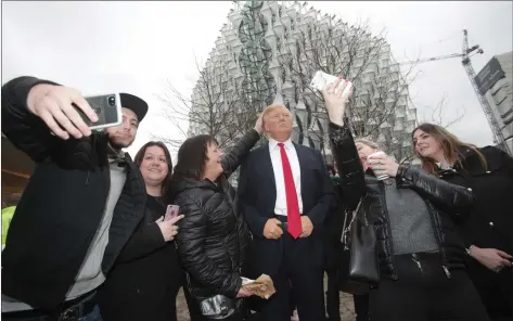  ??  ?? Passers-by take selfies with the Madame Tussauds wax figure of US President Donald Trump outside the new US embassy in Nine Elms, London.