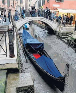  ?? Picture: AFP ?? A gondola lies idle in a canal where the water has dried up as low tides strike