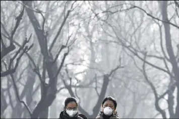  ?? ANDY WONG / ASSOCIATED PRESS 2016 ?? Chinese women wear masks to protect themselves from air pollution amid dense smog in Beijing in December. China’s collaborat­ion on climate with former President Barack Obama had been seen as a bright spot in the bilateral relationsh­ip. But President...