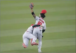  ?? Jeff Chiu Associated Press ?? BRIAN GOODWIN of the Angels collides with second baseman Tommy La Stella after catching a f ly ball by the A’s Chad Pinder during the second inning of Friday’s season opener in Oakland.