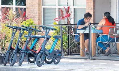  ?? JOE BURBANK/ORLANDO SENTINEL ?? Different brands of scooters are parked on the sidewalk in front of Eden’s Fresh Co. on Central Boulevard in downtown Orlando on June 28. The Orlando City Council is planning to extend the ongoing market testing of battery-powered scooters available for rent in downtown, but may consider limiting the number of vendors and scooters.