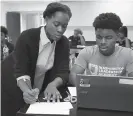  ??  ?? Britney Wray, a math teacher at the Washington academy, helps sophomore Kevin Baker with a math problem during class.