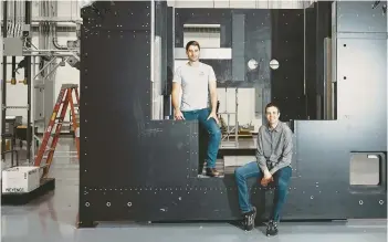  ?? SIMON SIMARD/THE NEW YORK TIMES ?? VulcanForm­s founders Martin Feldmann, left, and John Hart pose June 2 with the frame of a 3D printer at their facility in Devens, Mass.