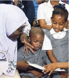  ?? K ENYON HEMANS ?? Marufah Tijani, principal of the Islamiyah Basic School, reads to her students at the Carlong Publishers Basic School Donation at the Kingston and St Parish Library, Tom Redcom Drive, Kingston, yesterday.