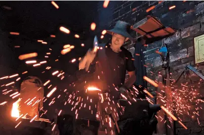  ??  ?? A blacksmith demonstrat­es hammering an iron piece at a workshop for handmade woks in Datian Village of central China’s Hubei Province in this August 13, 2018, photo. — Reuters