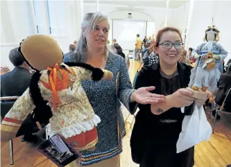  ?? CLIFFORD SKARSTEDT/EXAMINER ?? Co-organizer Nikki Auten, left, displays a no face doll next to Dawn Martin holding a corn husk doll for a silent auction during the inaugural Flint Corn Community Project, a traditiona­l Indigenous dinner (three course feast), movie fundraiser and a...