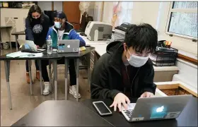 ?? ASSOCIATED PRESS FILE PHOTO ?? Student Tai Nguyen, right, works on his laptop as instructor Chaya Baras, left, helps student Kenny Scottborou­gh, 19, navigate an online lesson at West Brooklyn Community High School in New York.