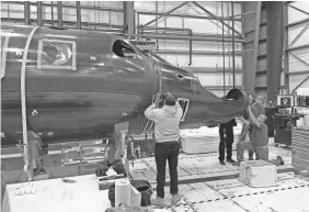  ??  ?? Virgin Galactic engineers work on one of two more SpaceShipT­wo crafts that are in progress at the company’s headquarte­rs in Mojave, California.