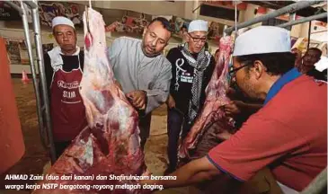  ??  ?? AHMAD Zaini (dua dari kanan) dan Shafirulni­zam bersama warga kerja NSTP bergotong-royong melapah daging.