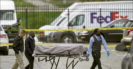  ?? MICHAEL CONROY / Ap ?? A body is taken from the scene Friday where multiple people were shot the night before at a Fedex Ground facility in Indianapol­is, Ind.