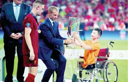  ?? AP ?? UEFA President Aleksander Ceferin and Ali Turganbeko­v, from Kazakhstan, right, hand the trophy to Liverpool’s team captain Jordan Henderson after Liverpool won the UEFA Super Cup.