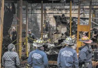  ?? Santiago Mejia / The Chronicle 2016 ?? Oakland firefighte­rs watch as federal agents inspect the remains of the Ghost Ship, an artists’ enclave that was destroyed in a blaze that claimed the lives of 36 people on Dec. 2, 2016.