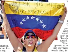  ??  ?? A supporter of Guaido holds a Venezuelan national flag reading ‘For my children, for my grandchild­ren’ as she waits for his return in Caracas. — AFP photo