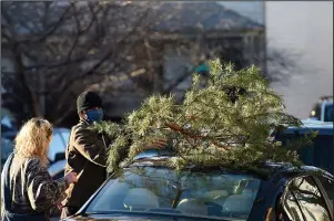  ?? A CHARLIE BROWN CHRISTMAS: The Associated Press ?? Parker Vivier and Marsden Olsen, both of Richmond, prepare to tie their tree to their car after purchasing from Frank Pichel’s tree lot on Dec. 6 in Richmond.