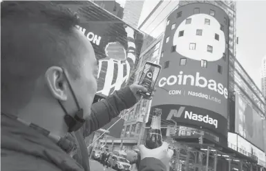  ?? RICHARD DREW/AP ?? Coinbase employee Daniel Huynh holds a bottle of Champagne as he takes a picture Wednesday outside the Nasdaq MarketSite in New York’s Times Square. The digital currency exchange became a publicly traded company earlier this week.