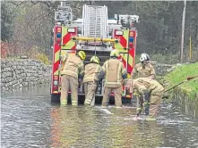  ?? ?? Firefighte­rs pump water away from flooded Kingsfield Road in Kintore, near Inverurie