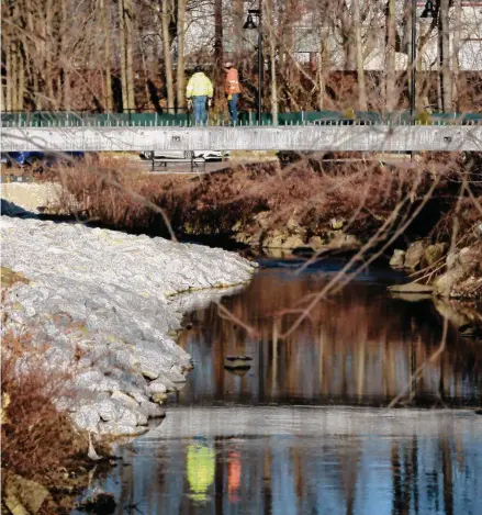  ?? H John Voorhees III/Hearst Connecticu­t Media file photo ?? Above and below, workers install a section of a bridge earlier this year over Padanaram Brook that runs between a 149-apartment complex being developed on Main Street and Brookview Commons, another building owned by the developer BRT on Crosby Street in Danbury.