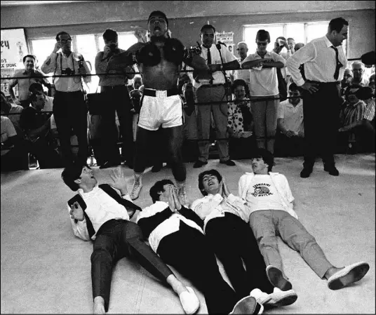  ?? THE ASSOCIATED PRESS ?? Boxer Cassius Clay — later Muhammad Ali — playfully beats his chest in triumph after toppling Britain’s celebrated Beatles at his training camp in Miami Beach, Fla., in this photo taken Feb. 18, 1964. The Beatles, from left, Paul McCartney, John...