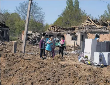  ?? Photo / AP ?? Residents in Bakhmut, Donetsk region, stand in a crater after Russian airstrikes destroyed residentia­l areas.