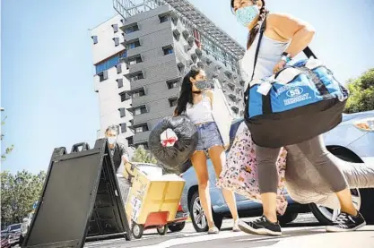  ?? SANDY HUFFAKER ?? Holly Fleurbaaig moves her belongings into her dormitory at UC San Diego on Saturday with the help of her parents Chantelle and Graham. About 7,500 undergradu­ate students are expected to move into campus housing in the week before school starts.